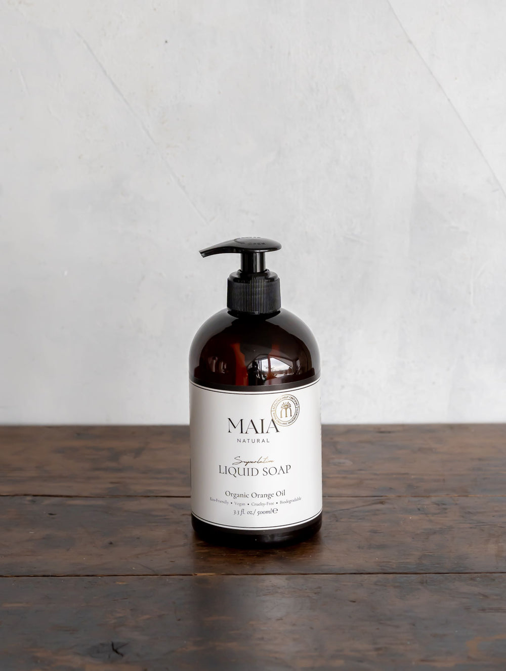 A pump bottle of Maia Natural Liquid Hand Soap on a wooden surface.